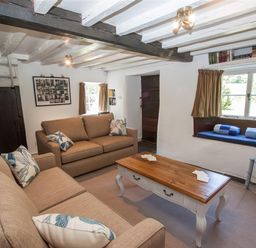 A living room with two sofas a wooden coffee table a TV on a stand and a window seat at The Cragg in Hawkshead