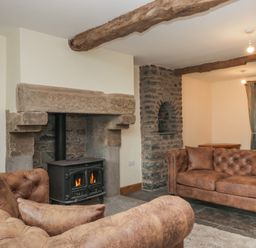 A living room with a fireplace and sofas at Howgill Head in Kendal