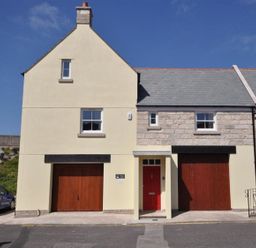 A street view of a house with two wooden garage doors and a red entrance door at Sunset Lodge in Fortuneswell