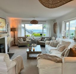 A living room with sofas armchairs a coffee table and a fireplace at Trem Ynys 3 bed in Abersoch