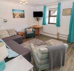 A living room with a sofa and television at Puffin Nook in Broad Haven