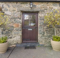 An entrance door surrounded by stone wall and planters at Cyffdy Cottage - Arenig in Bala