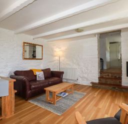 A living room with a leather sofa wooden coffee table and a television at Babes Cottage in Perranwell near Goonhavern