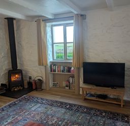 A living room with a fireplace and a tv at Babes Cottage in Perranwell near Goonhavern