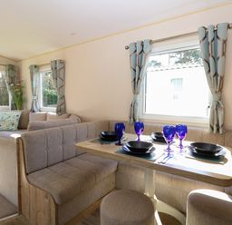 A dining area with a table set with blue glasses and black dishes next to a beige seating area at 4 Foxburrow Hang in Fritton near Belton Norfolk