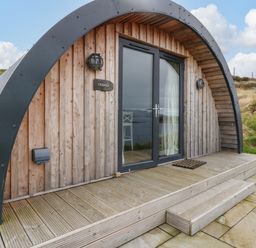 A wooden pod with curved roof and glass double doors on a wooden deck at Creags in Cullipool Isle Of Luing