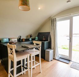 A kitchen area with two high chairs a countertop toaster and double glass door leading outside at Creags in Cullipool Isle Of Luing