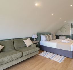 A bedroom with a green sofa a bed with pillows folded towels and a small sink at Sula in Cullipool Isle Of Luing