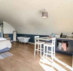 A room with a bed white chairs kitchenette and a bathtub at Scarba in Cullipool Isle Of Luing