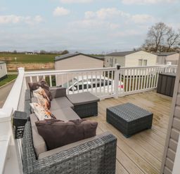 An outdoor deck with a wicker sofa a matching coffee table and a storage box at Meadow View in West Thirston Felton