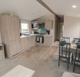 A kitchen with wooden cabinets and a dining table set with plates and glasses at Meadow View in West Thirston Felton