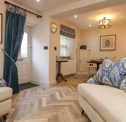 A living room with beige sofas blue patterned cushions a dining table with chairs and framed artwork at 6 Uppergate Street Rose Cottage in Conwy