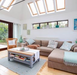 A living room with a large sofa coffee table and skylights at Goatsland in Trebetherick