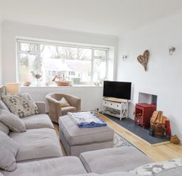 A living room with a sectional sofa an armchair a wood stove and a television at 3 Glyn Y Mor in Llanbedrog