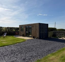 A container structure in a grassy area at Caban in Dothan near Gwalchmai