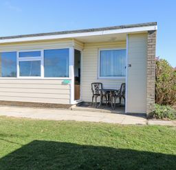 A small patio area with metal table and two chairs outside a bungalow at Chalet 39 in Hemsby