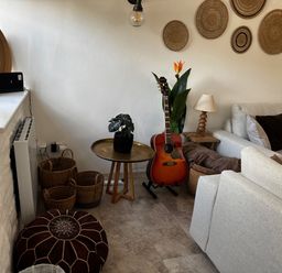 A living room with a guitar and plants at Bracken Cottage in Osmington