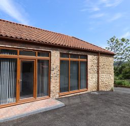 An outdoor space with a brick wall and windows at Birch Cottage in Scarborough