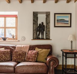 A living room with a sofa and sculptures at Y Bwthyn in Llangrannog
