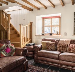A living room with sofas and stairs at Y Bwthyn in Llangrannog