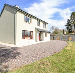 A two-story house with a gravel driveway and green grass lawn at Teach Ards Kilgarvan County Kerry