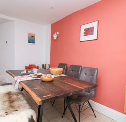 A dining area with a wooden table, chairs, a bench with a fur cover, and food on the table at Joymead in Malborough
