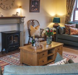 A living room with a fireplace armchairs coffee table and sofa at Beaver Cottage Little Thirkleby near Thirsk