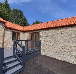 An outdoor area with a stone wall and wooden decking at Castle View in Scarborough
