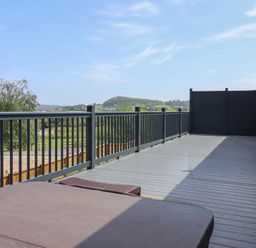 An outdoor deck with a hot tub and railing at Castle View in Scarborough