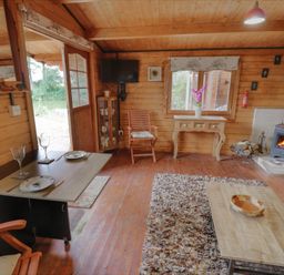 A living room with a wooden floor and stove at Carps Well Lodge Hatton near Shrewley