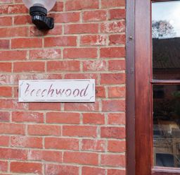 A brick wall with a nameplate reading Beechwood at Beechwood in Wood Norton