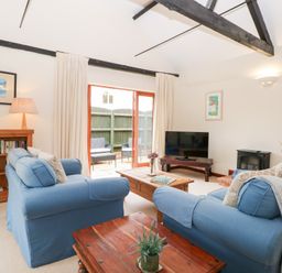 A living room with sofas, a television and a bookshelf at Willow in Wood Norton near Foulsham