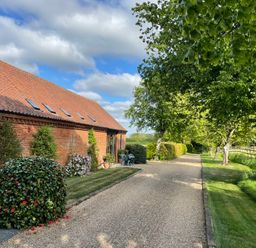 A garden pathway leading to a house with trees and shrubs at Pear Tree in Wood Norton