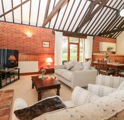 A living room with a television a sofa and a dining area at Pear Tree in Wood Norton