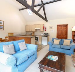 A living room with sofas and a kitchen area at Holly Berry in Wood Norton near Foulsham