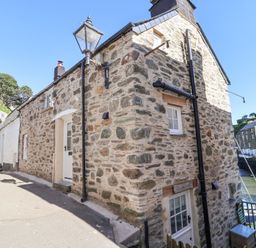 A narrow street with stone cottages and a lamp post by a waterfront at Harbour View in Polperro