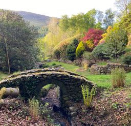 A garden with a stone bridge and various plants at High Cross in Keswick