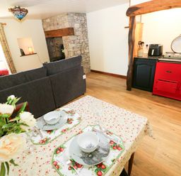 A living room with a sofa and kitchen stove at Dolcoed in Manordeilo near Llangadog