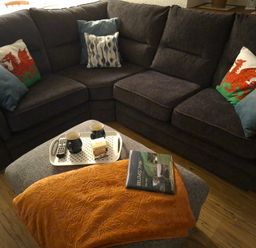 A living room with a sofa, cushions, mugs, and a book at Dolcoed in Llandeilo