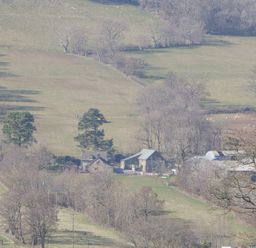 A rural farm with buildings surrounded by fields and trees at White Haywood Farmhouse & Barn in Craswall