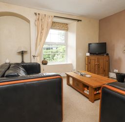 A living room with a television and coffee table at Sygun Cottage in Nant Gwynant