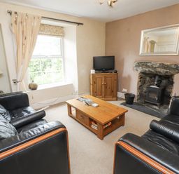 A living room with a sofa, coffee table, and television at Sygun Cottage in Nant Gwynant