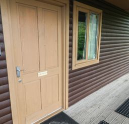 An exterior door with a keypad on the wall and a window on a wooden cabin at Sycamore in Cowbridge