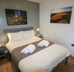 A bedroom with a double bed two bedside tables with lamps and framed pictures on the walls at Beech in Cowbridge