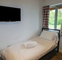 A bedroom with a single bed next to a window and a wall mounted television at Beech in Cowbridge