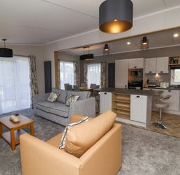 An open plan living room with sofas a coffee table kitchen and dining area at 16 Manleigh Park in Combe Martin
