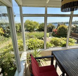 A conservatory with a table and chair overlooking a garden at Nanvivian in Feock near Truro