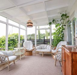 A conservatory with rattan chairs and a table at Nanvivian in Feock near Truro