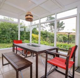A conservatory with a table and chairs at Nanvivian in Feock near Truro