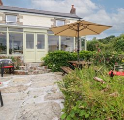 A garden with patio furniture and an umbrella at Nanvivian Feock near Truro